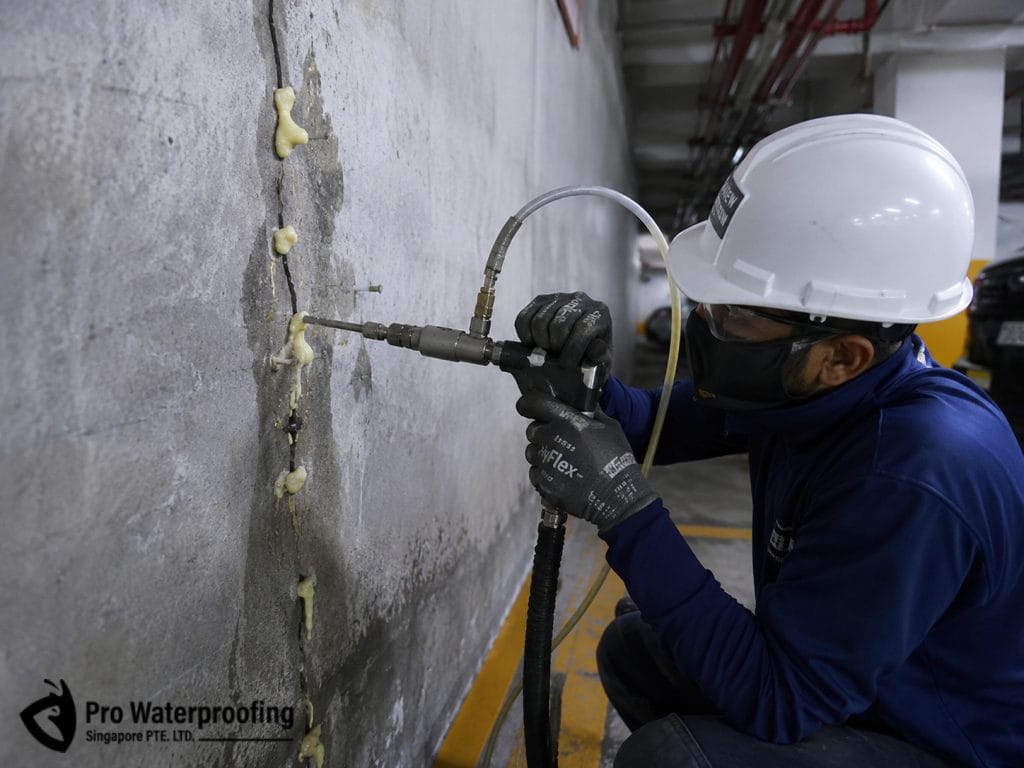 Professional technician applying high-pressure PU injection grouting to seal a concrete wall crack in Singapore.